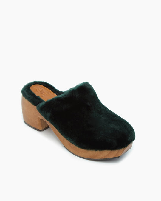 A dark green, plush, fur-lined clog with a wooden sole and a chunky heel.