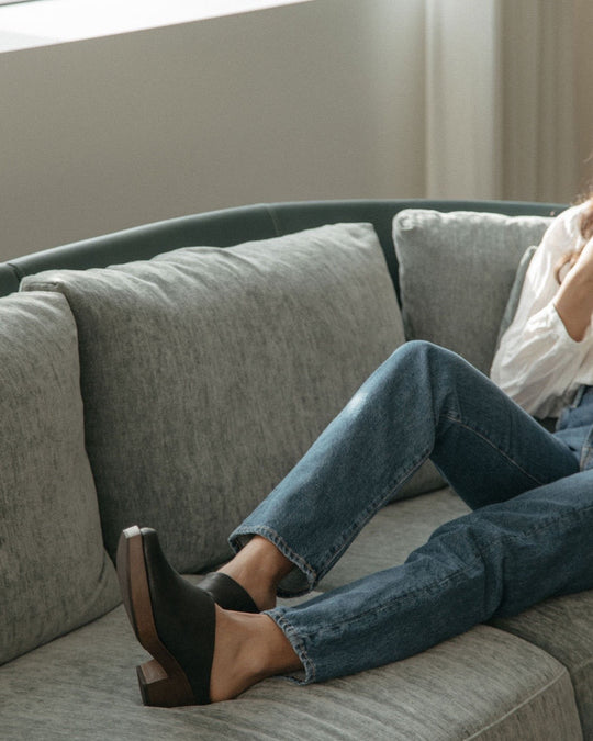 View of women's upper body and legs laying on a couch wearing jeans and a white shirt with the Kera Shearling Clog